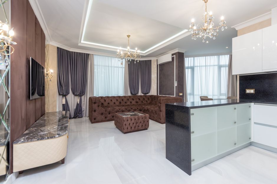 Spacious modern living room featuring elegant chandeliers, plush sofa, and contemporary decor.